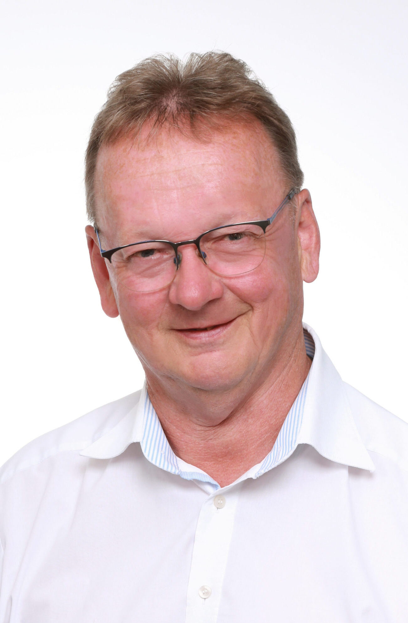 Porträtaufnahme eines Mannes mit Brille und weißem Hemd vor hellem Hintergrund.